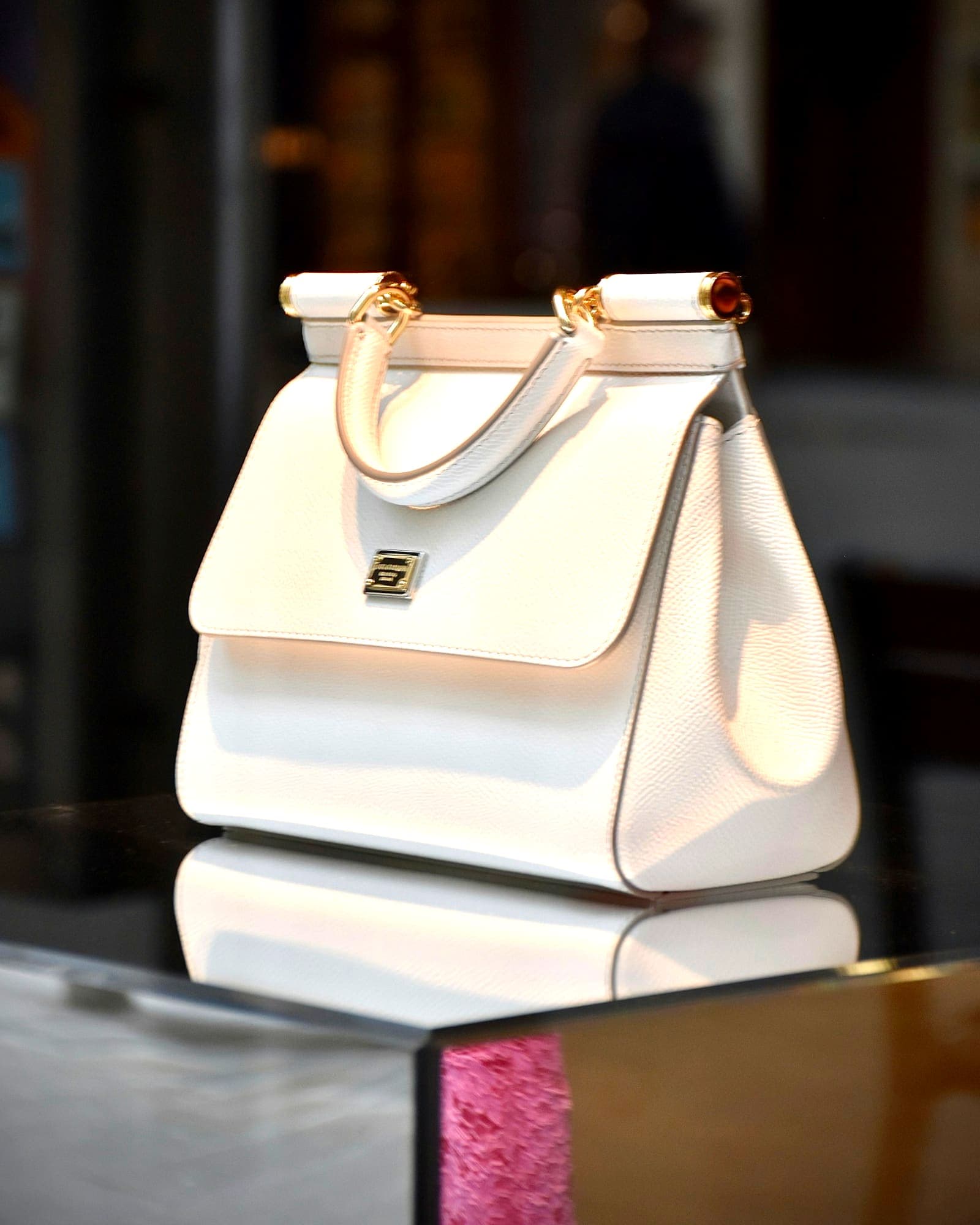 Cream leather top-handle bag with gold clasp, softly blurred background