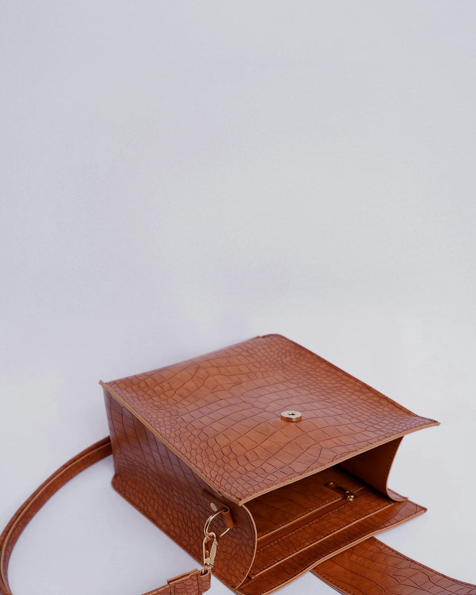 Cognac croc-embossed mini flap bag with a long strap, white background — detail view