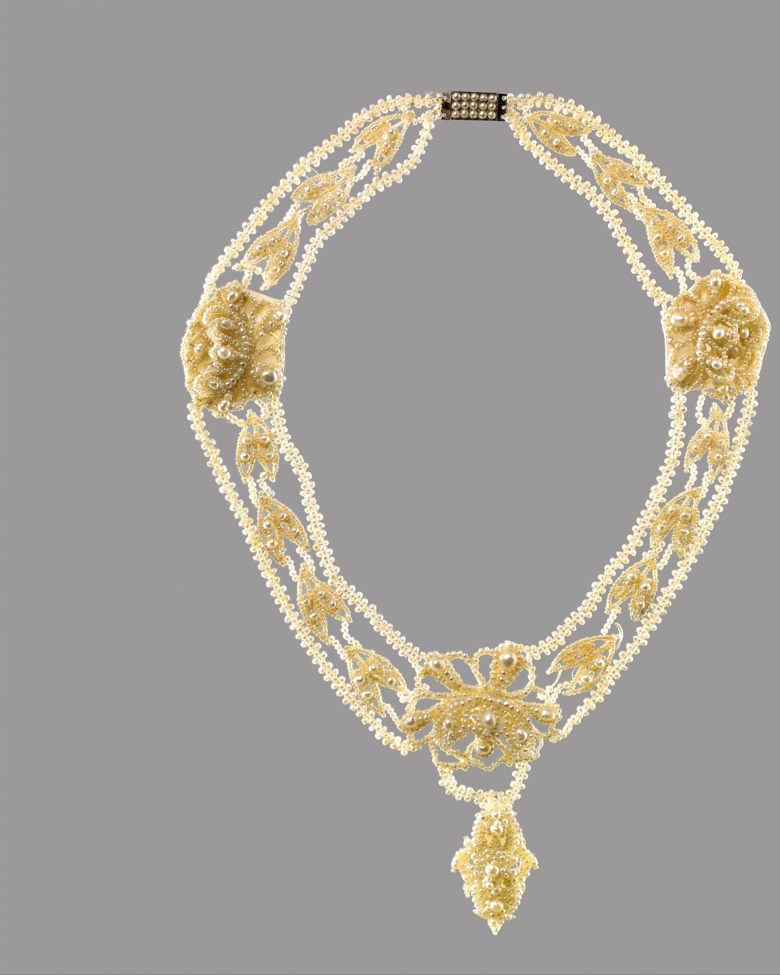 Pearl and diamond collar necklace on a grey background — detail view