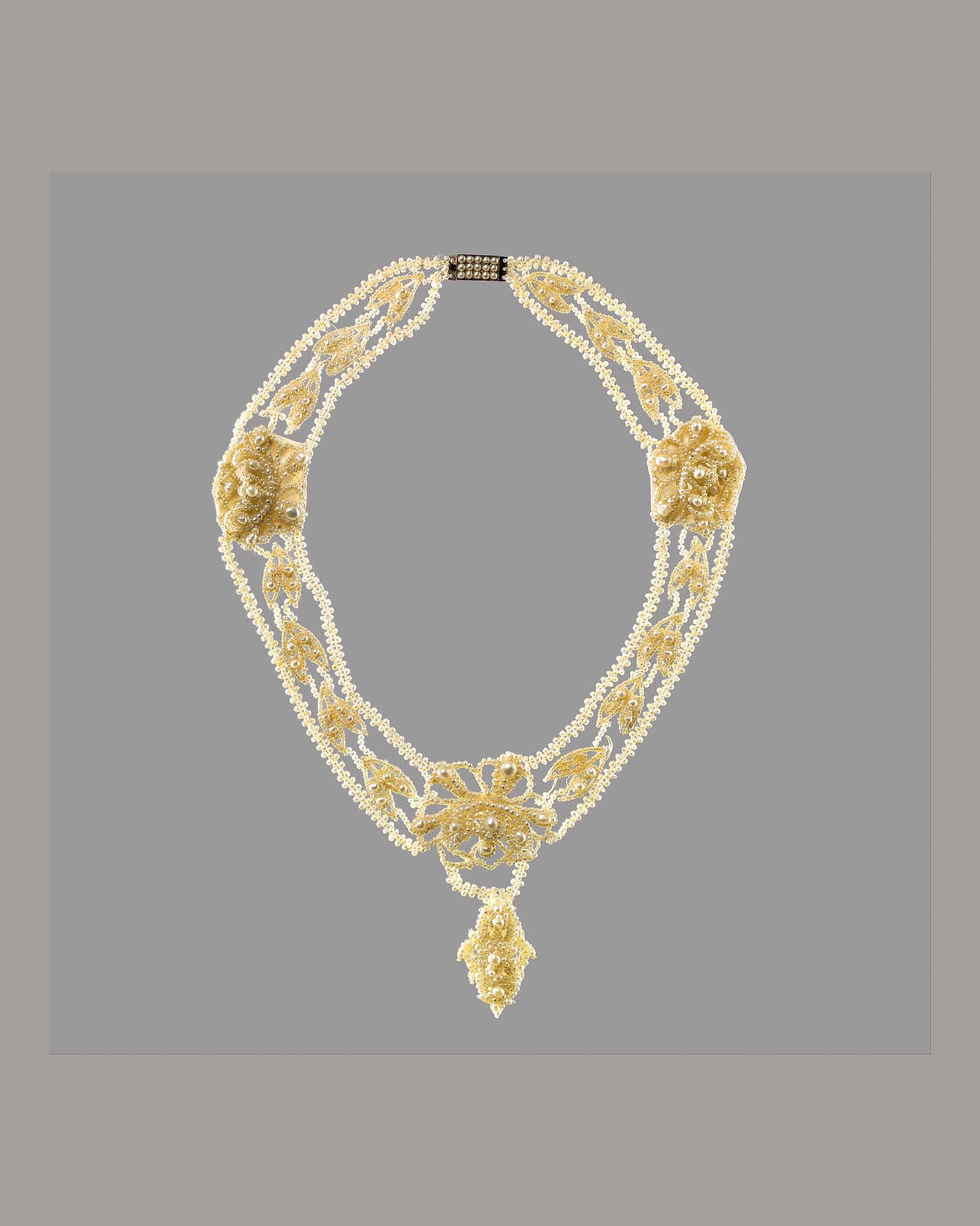 Pearl and diamond collar necklace on a grey background