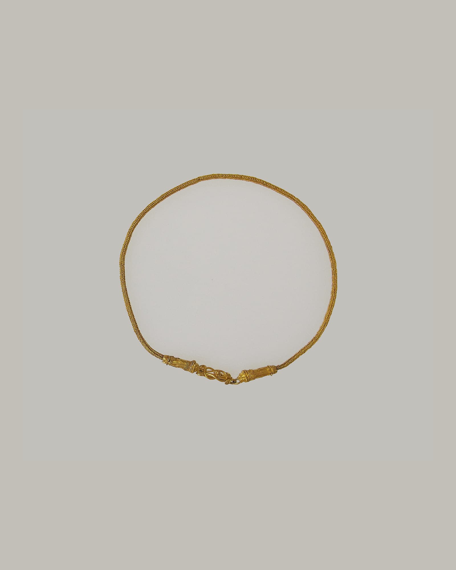 Slender yellow-gold collar necklace on a cream background