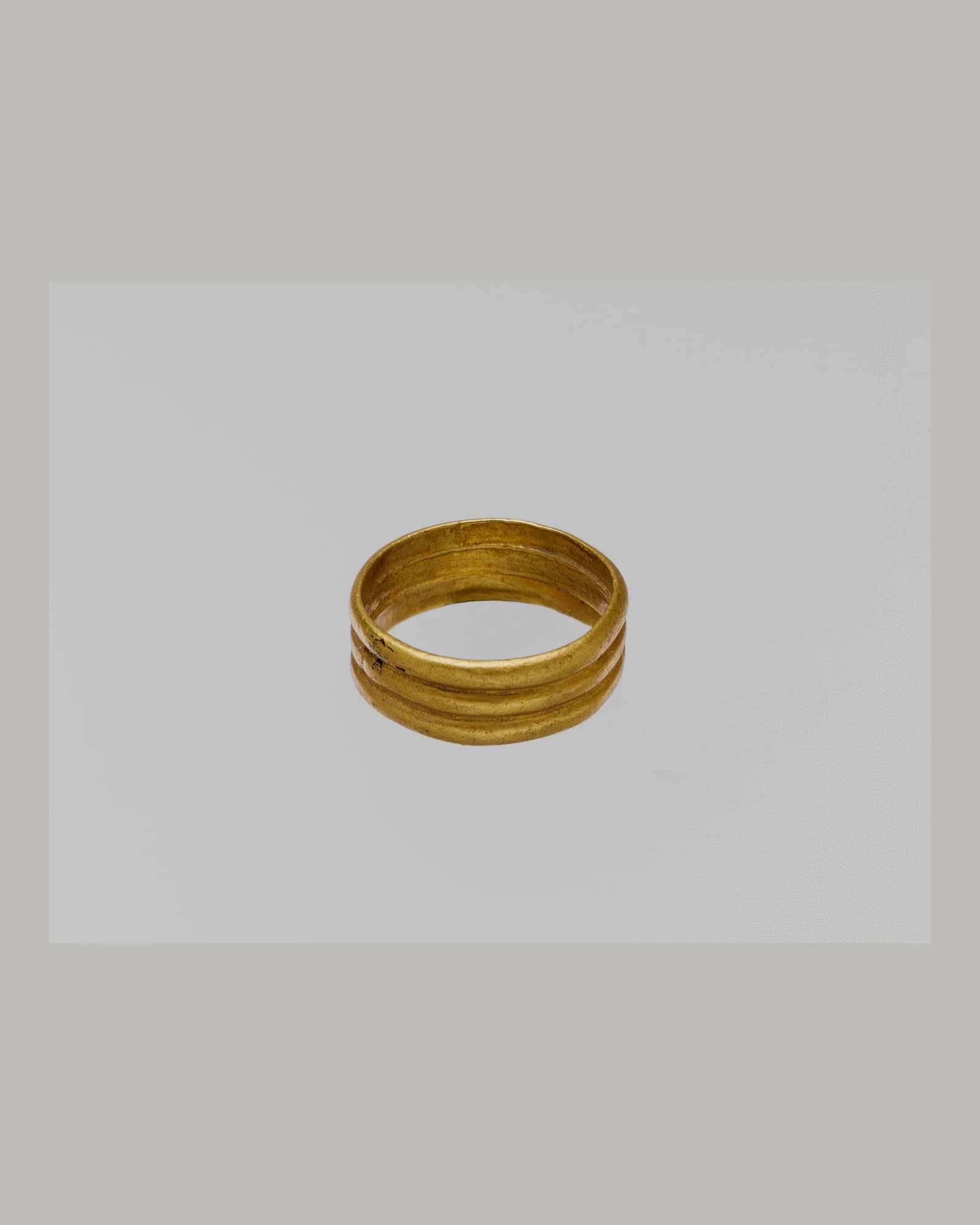 Plain yellow-gold band ring on a pale grey background