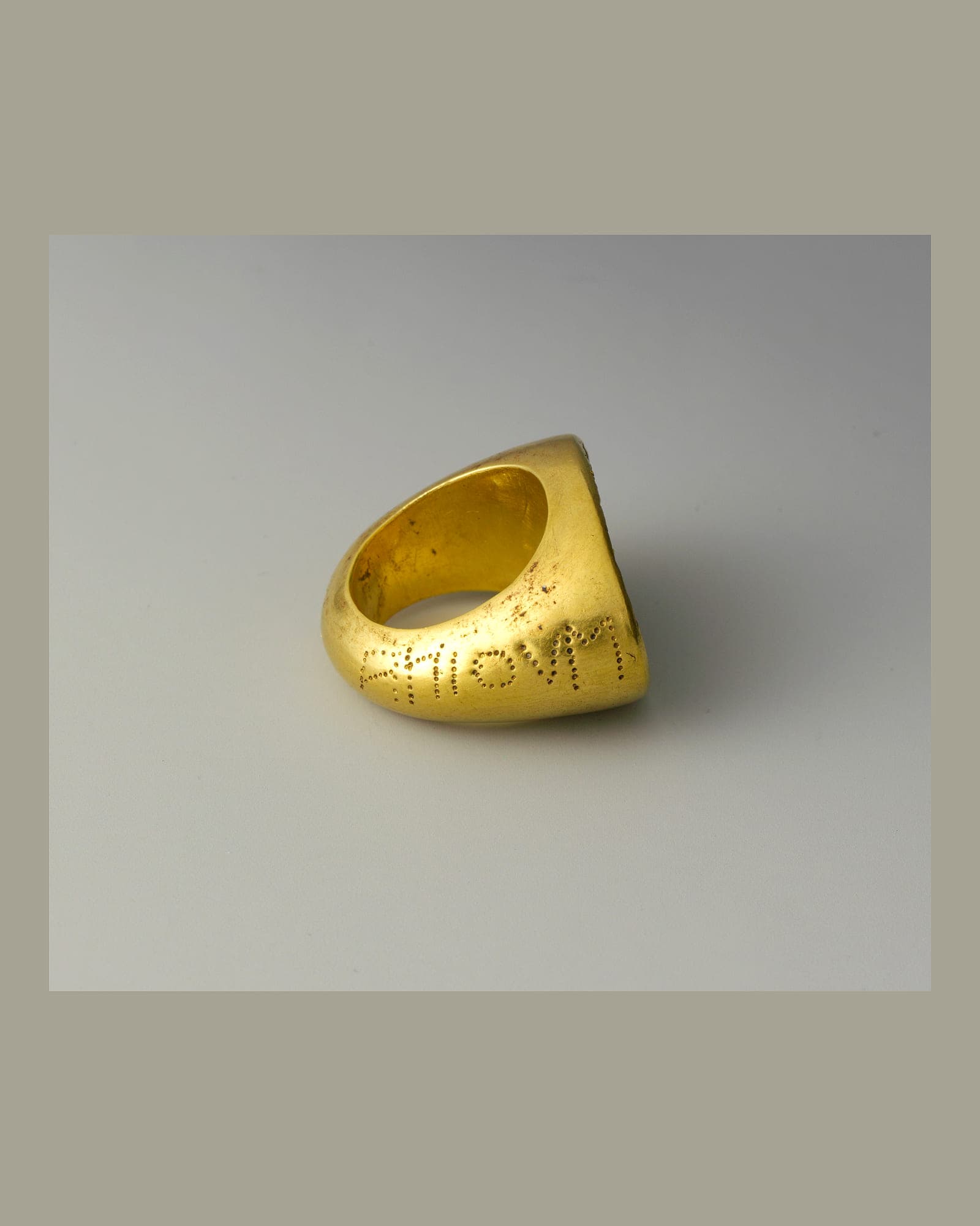 Heavy yellow-gold signet ring on a grey background