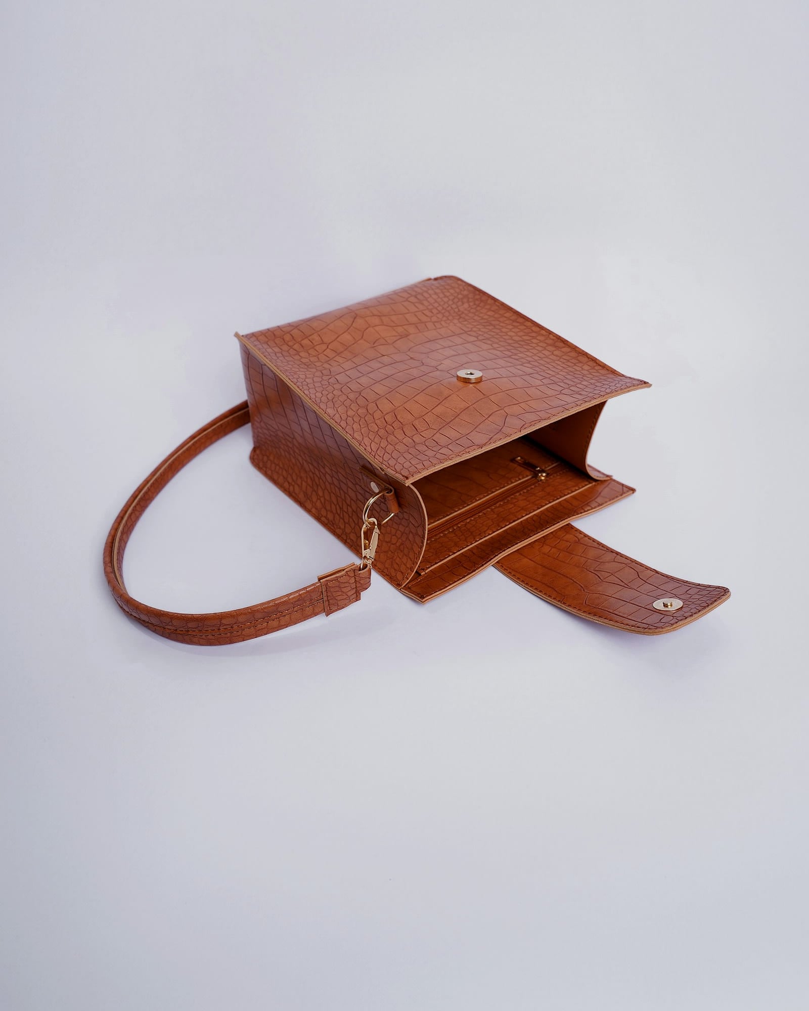 Cognac croc-embossed mini flap bag with a long strap, white background