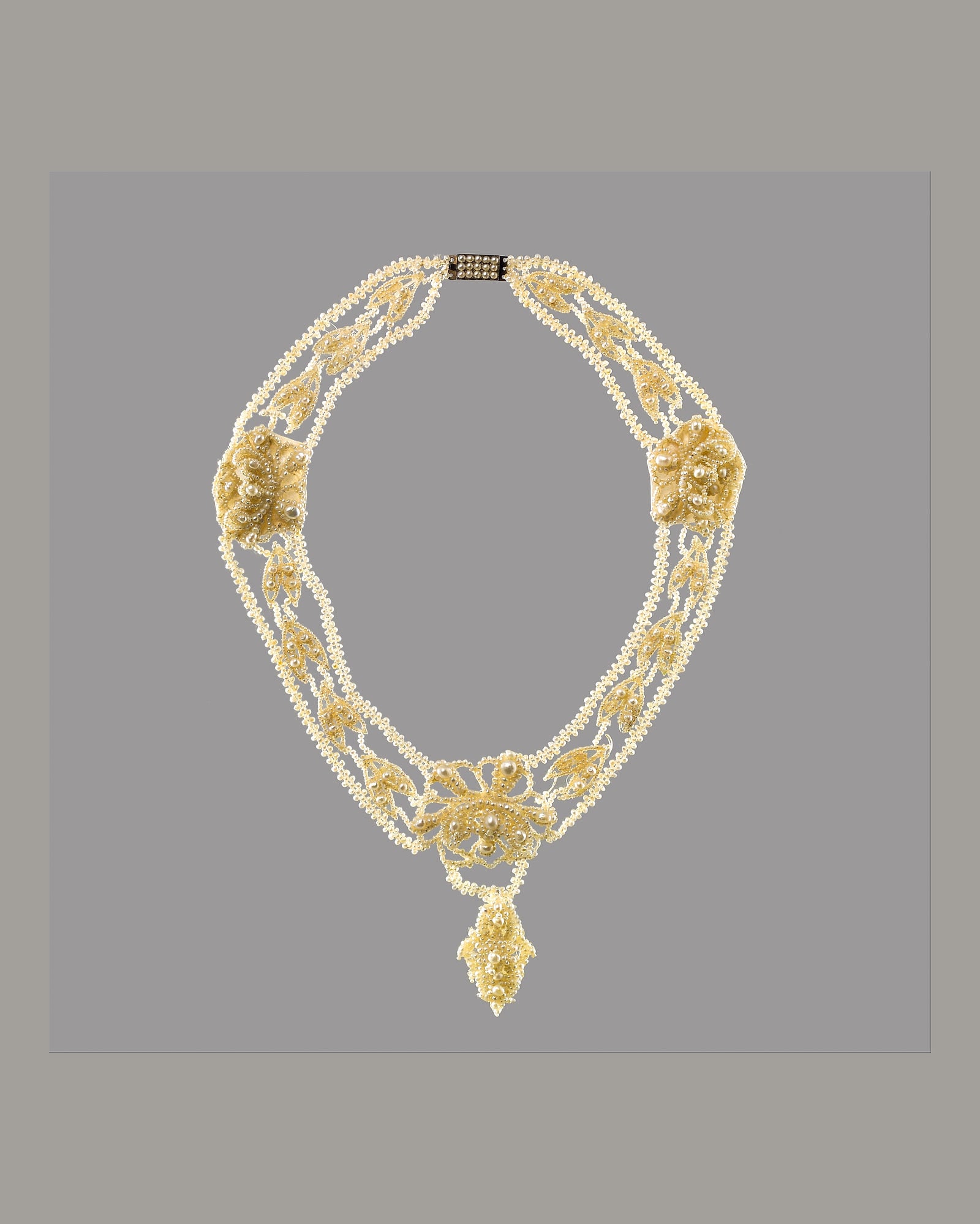 Pearl and diamond collar necklace on a grey background