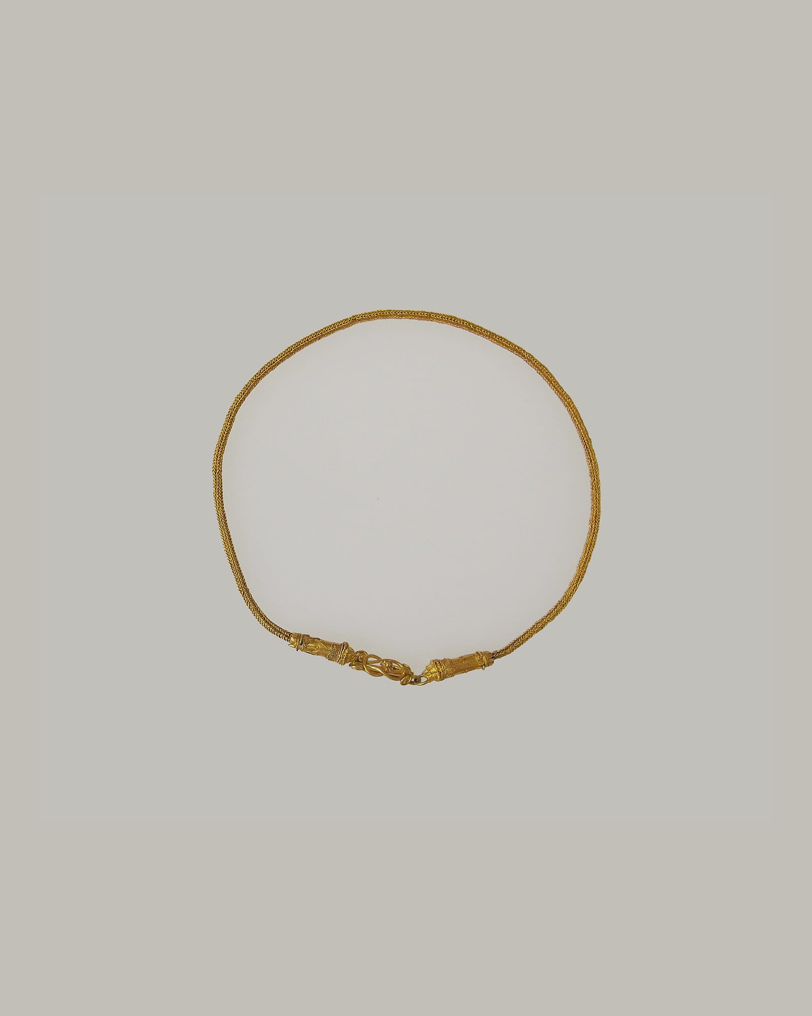 Slender yellow-gold collar necklace on a cream background
