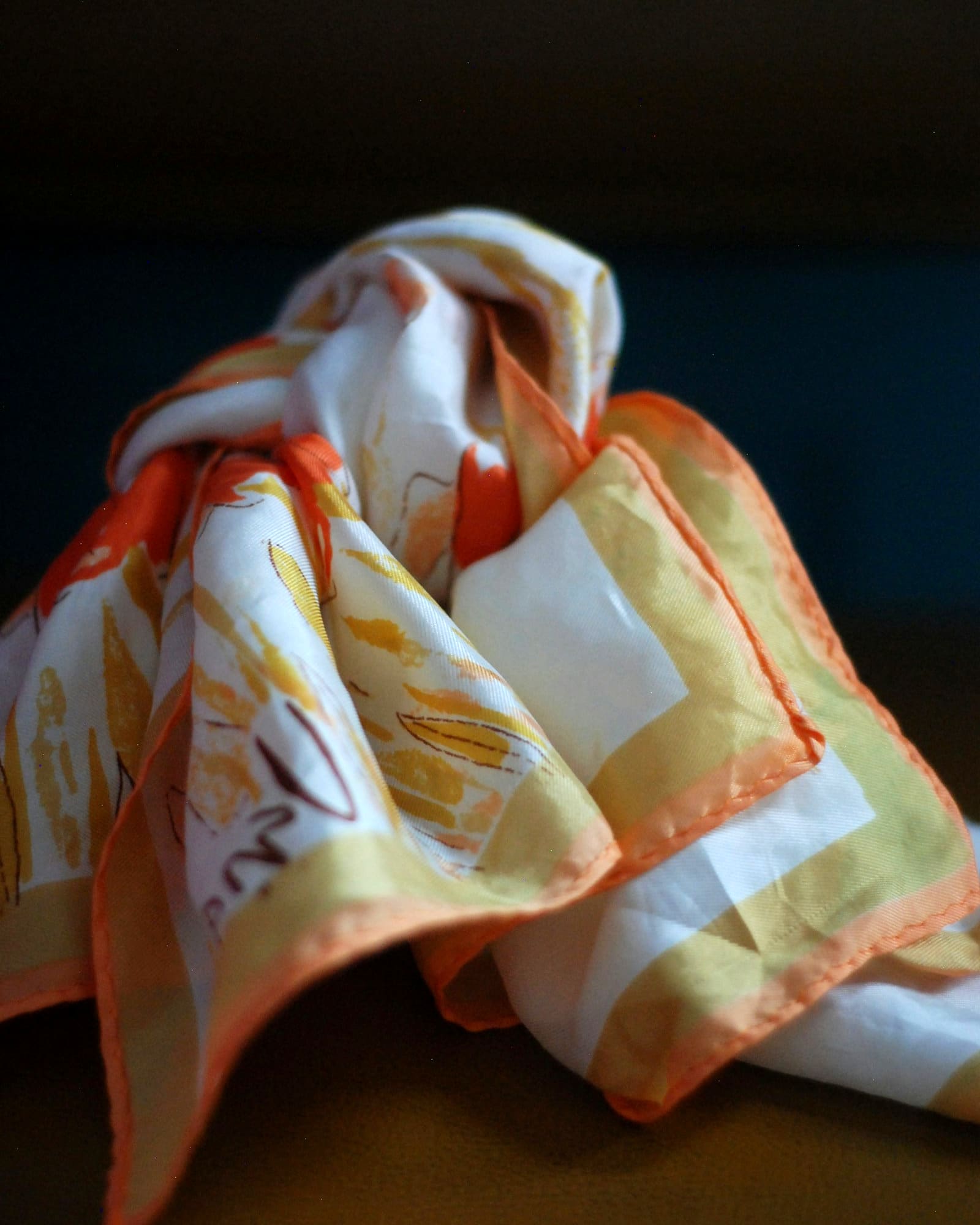 Ivory silk scarf with a coral border, loosely knotted