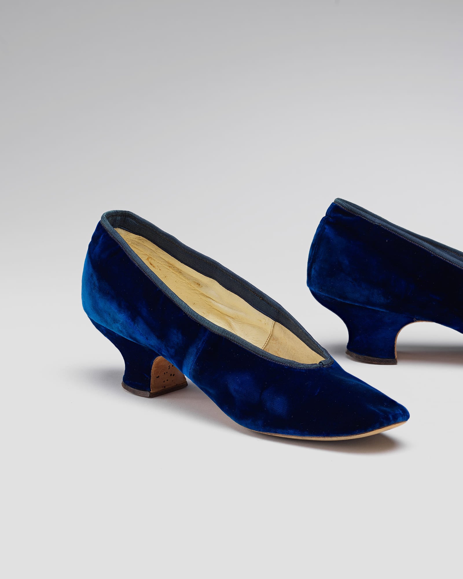 Pair of navy velvet flats, pale grey background — detail view