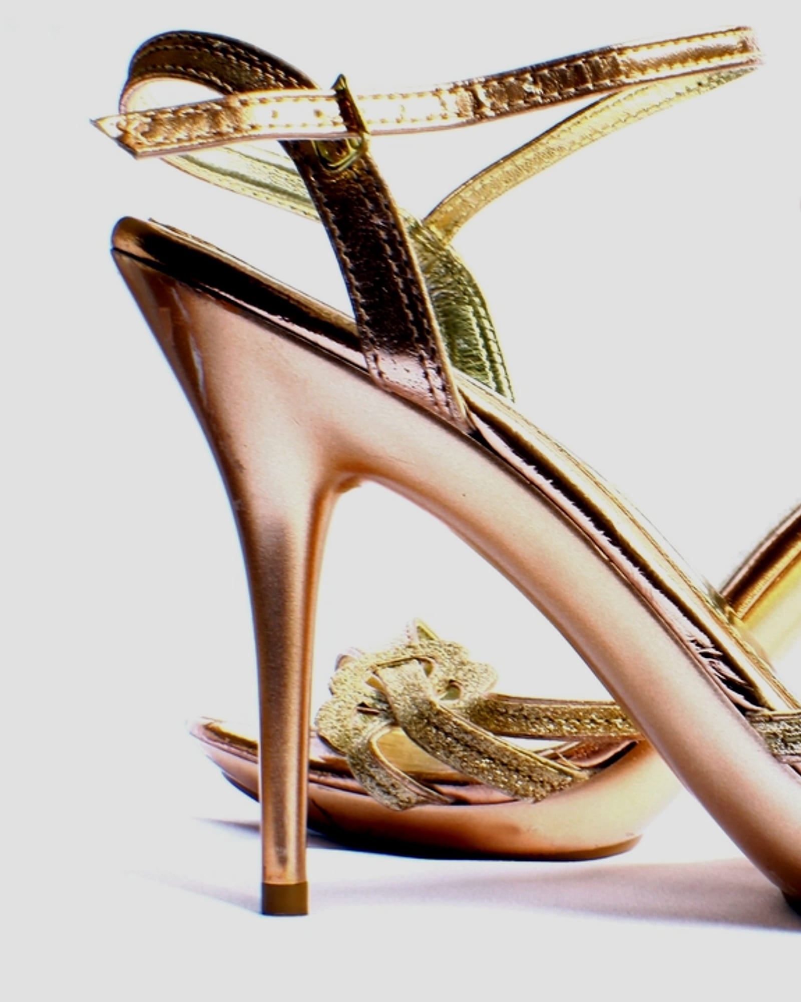 Rose-gold strappy high-heeled sandals, white background — detail view