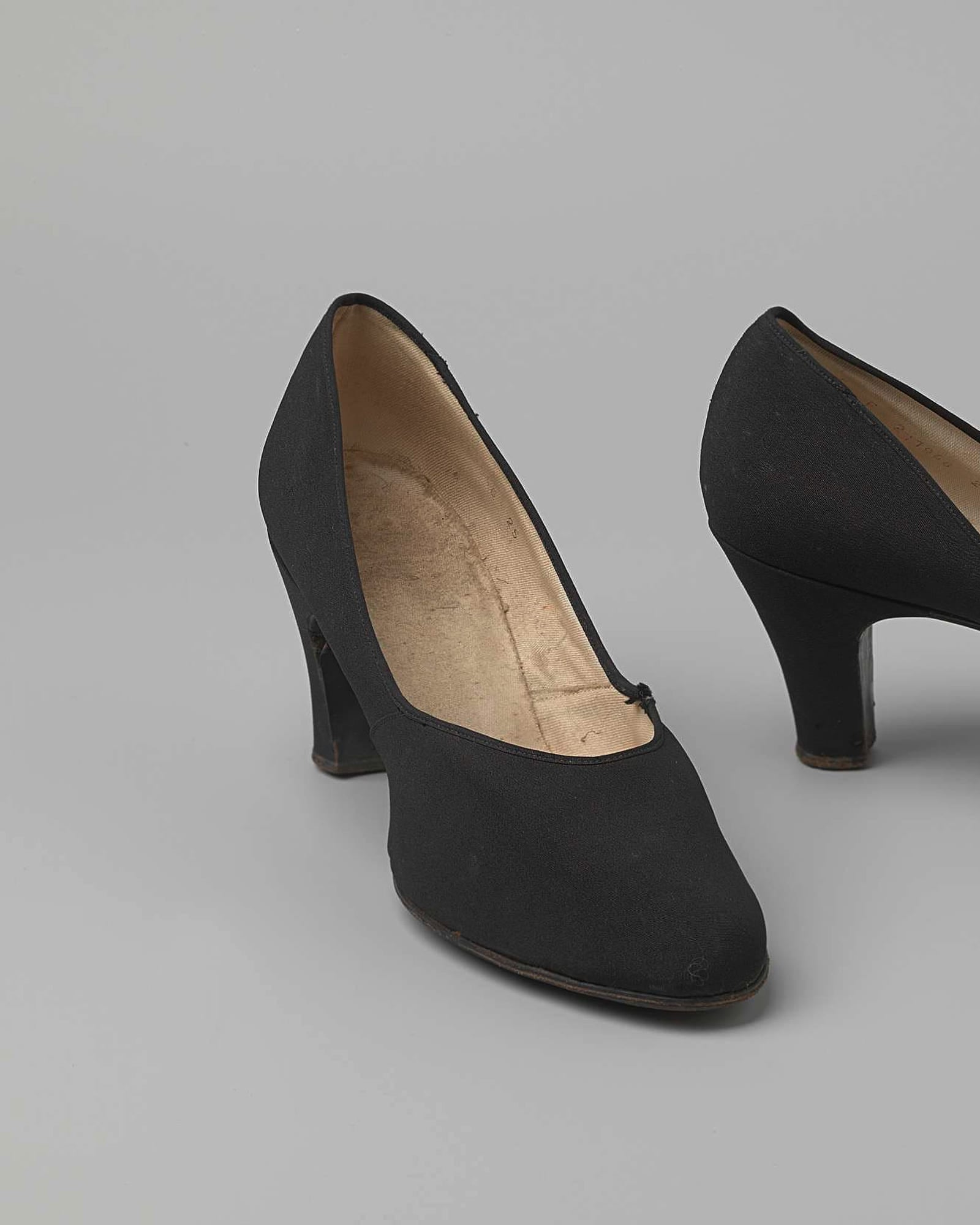 Pair of black suede block-heel pumps, grey background — detail view