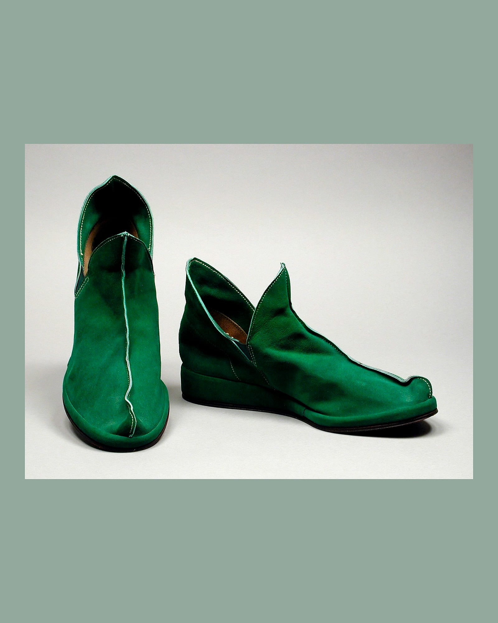Pair of emerald satin ankle boots, white background
