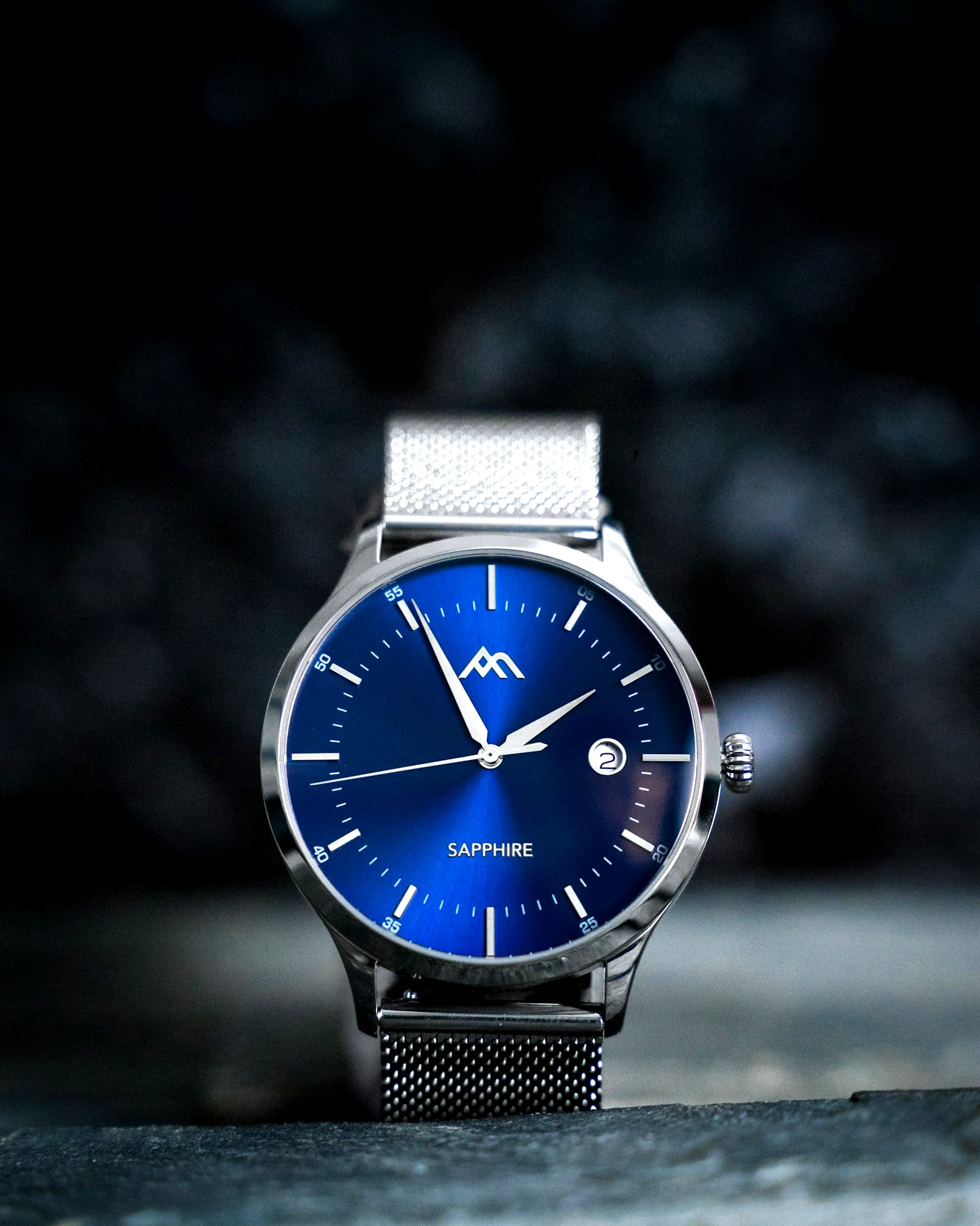 Steel watch with a sunburst blue dial on a woven mesh bracelet