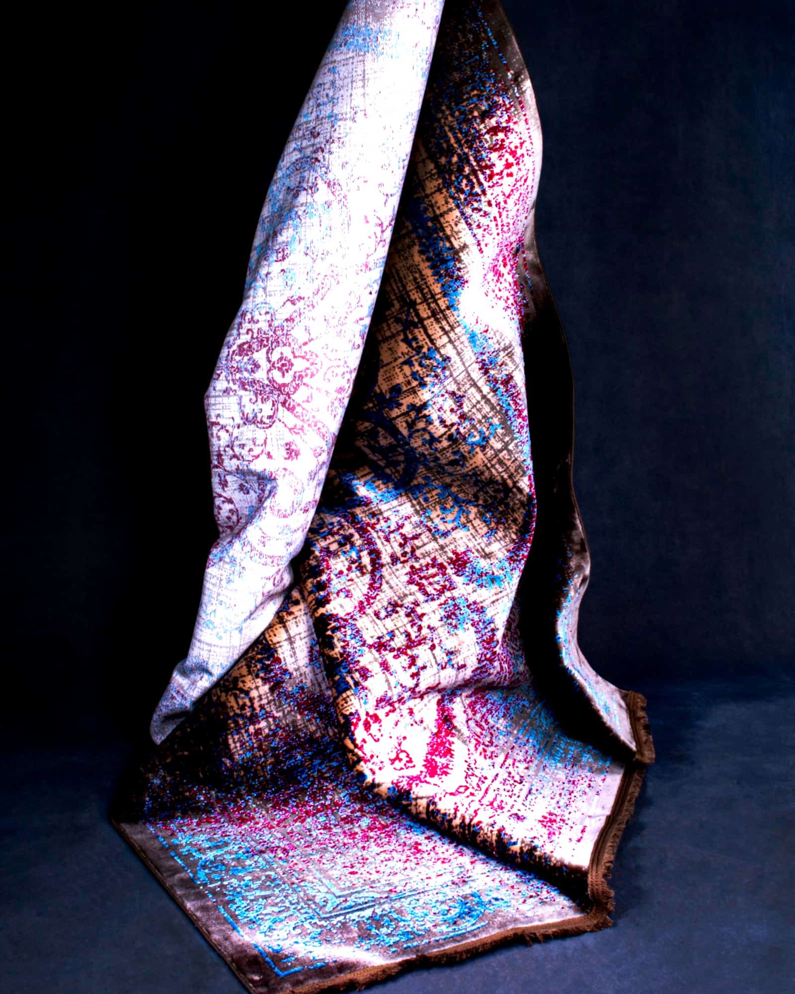 Lilac and slate paisley silk scarf draped over a dark ground