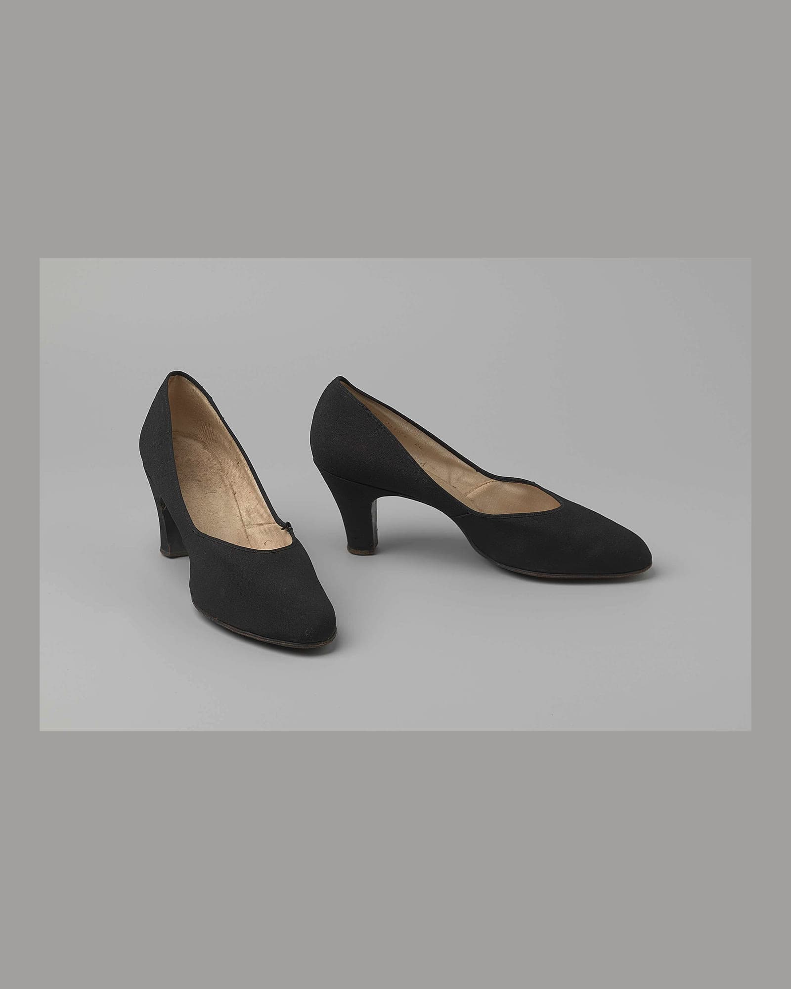 Pair of black suede block-heel pumps, grey background