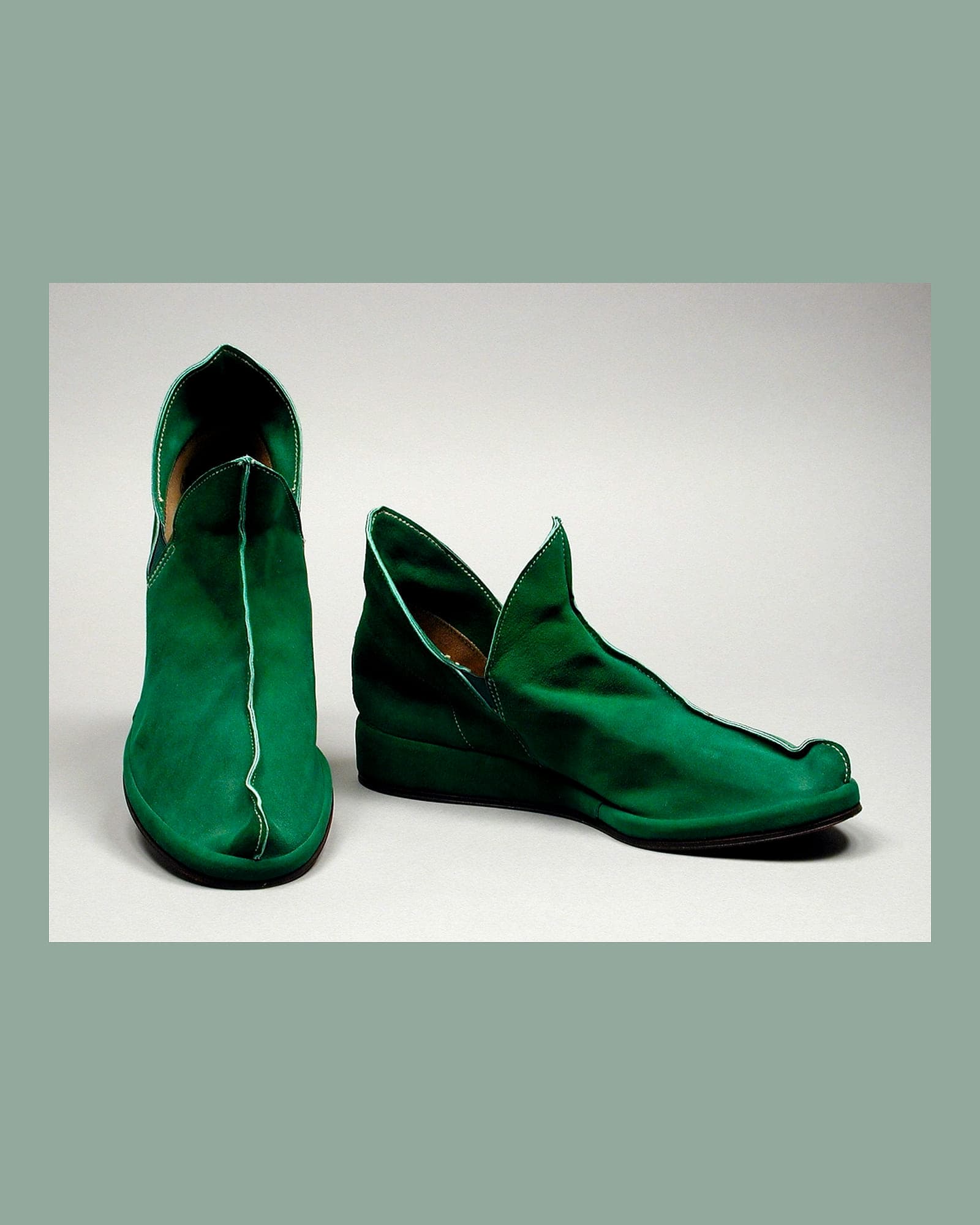 Pair of emerald satin ankle boots, white background